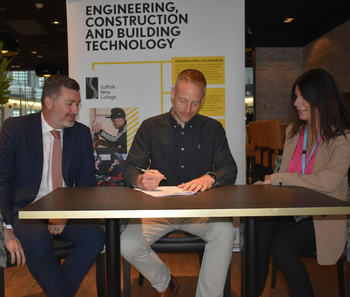 Alan Pease and Marianne Flack look on as Bryan from the SJCC signs a deal to work with Suffolk New College